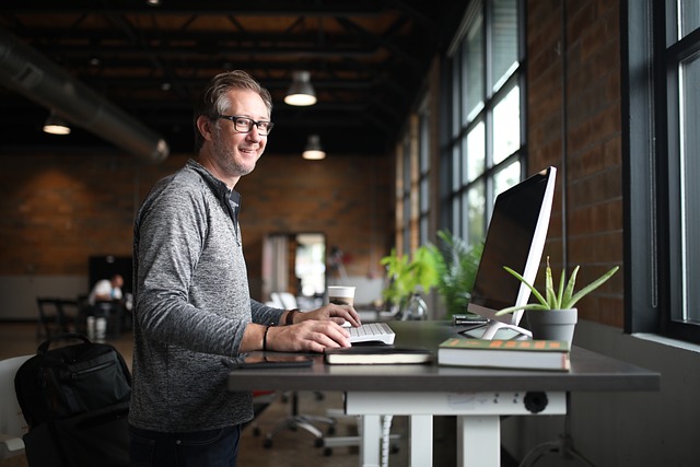 Image d'illustration : homme souriant devant un ordinateur